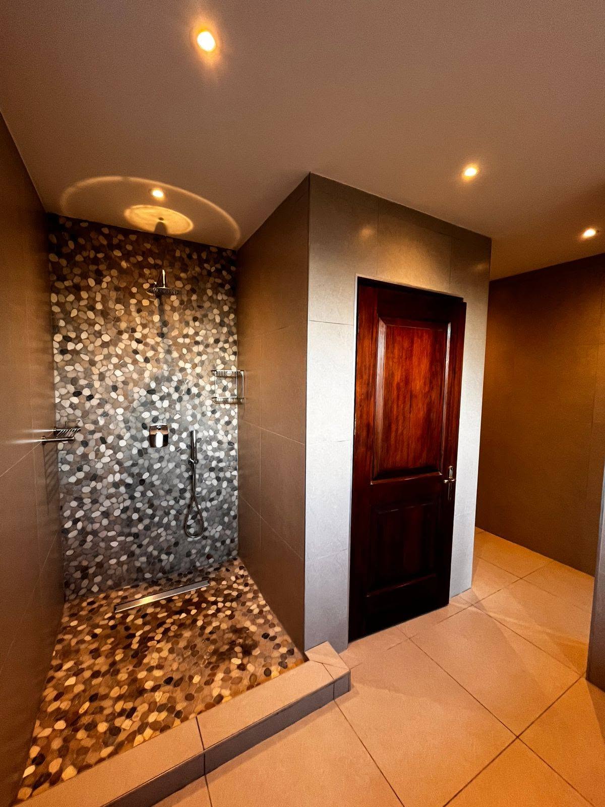 Walk-in pebble-tiled shower with rainfall head