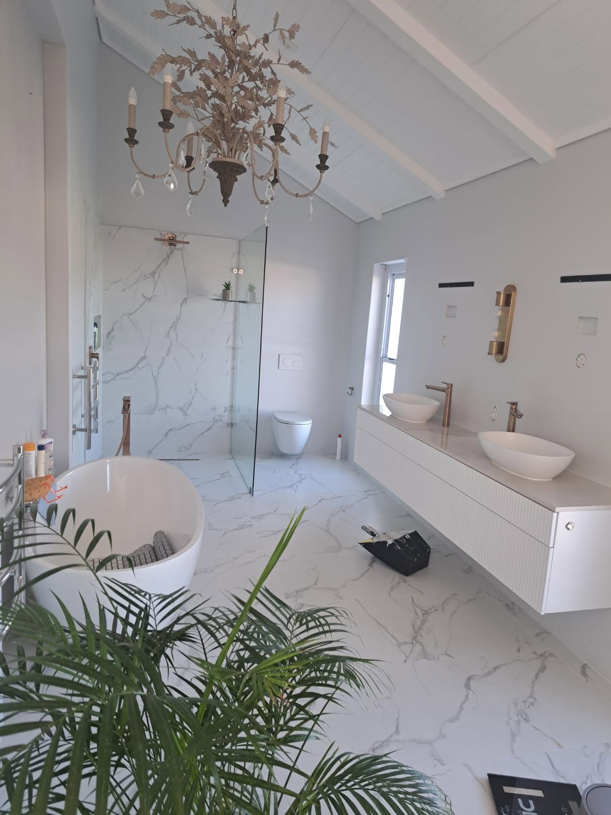 Finished luxury bathroom with marble finishes, freestanding bath and gold fixtures