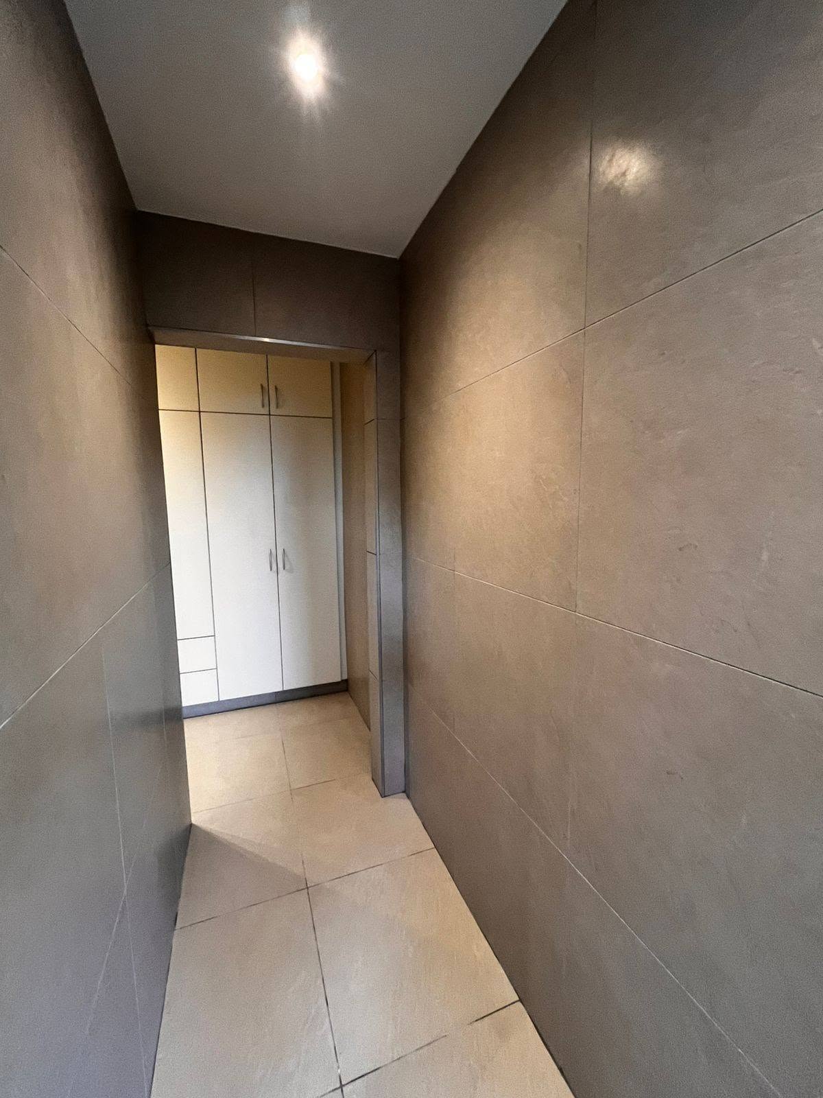 Large-format tiled passage and built-in cupboards