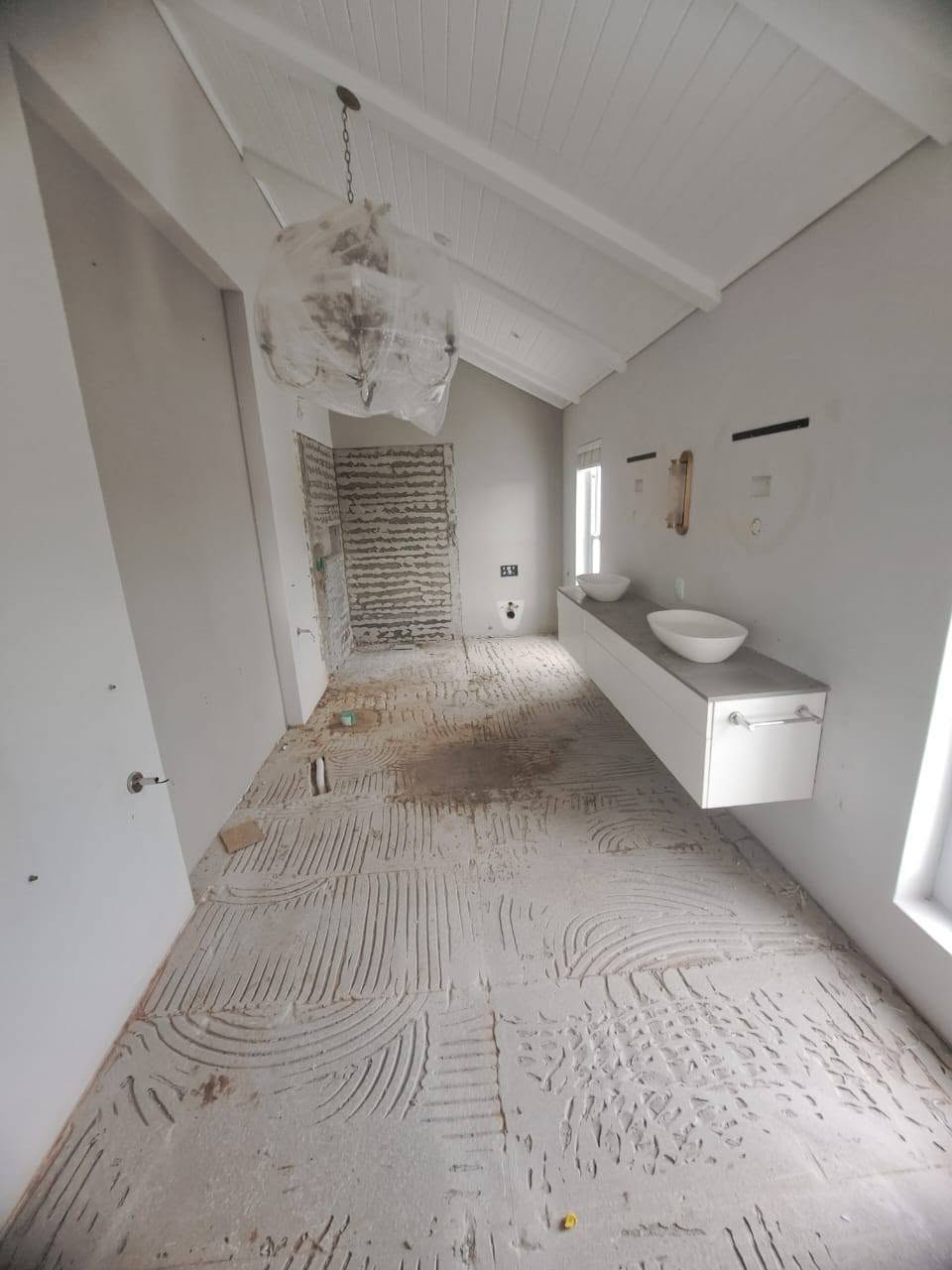 Bathroom mid-renovation with bare floors and unfinished walls